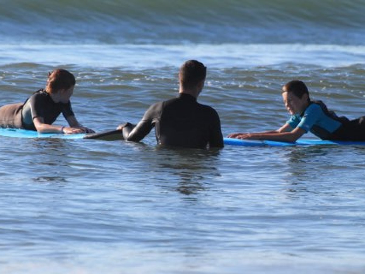 Three people on surfboards in the ocean, preparing to surf.