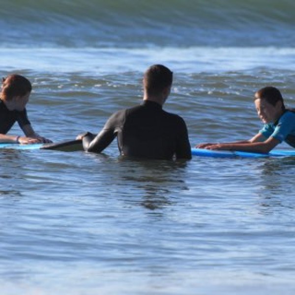 Three people on surfboards in the ocean, preparing to surf.
