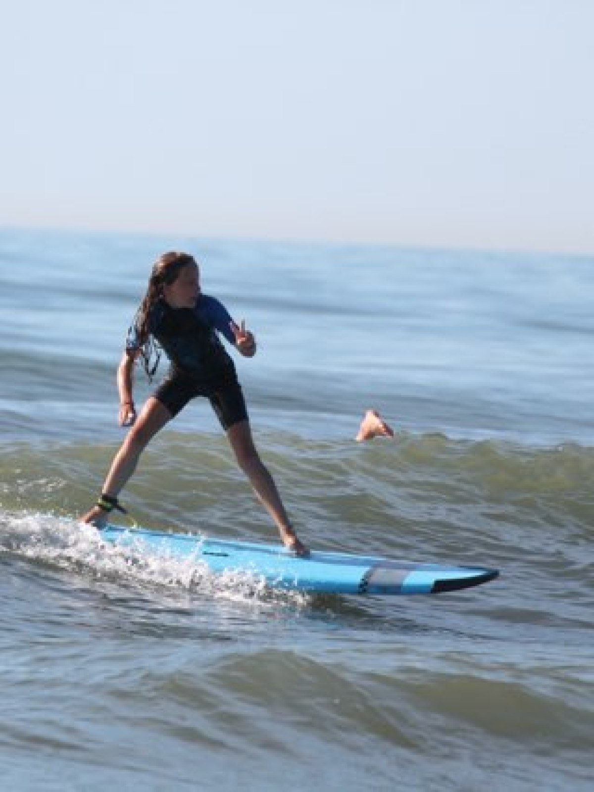 Person surfing on small waves with arm raised.