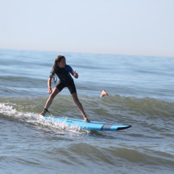 Person surfing on small waves with arm raised.